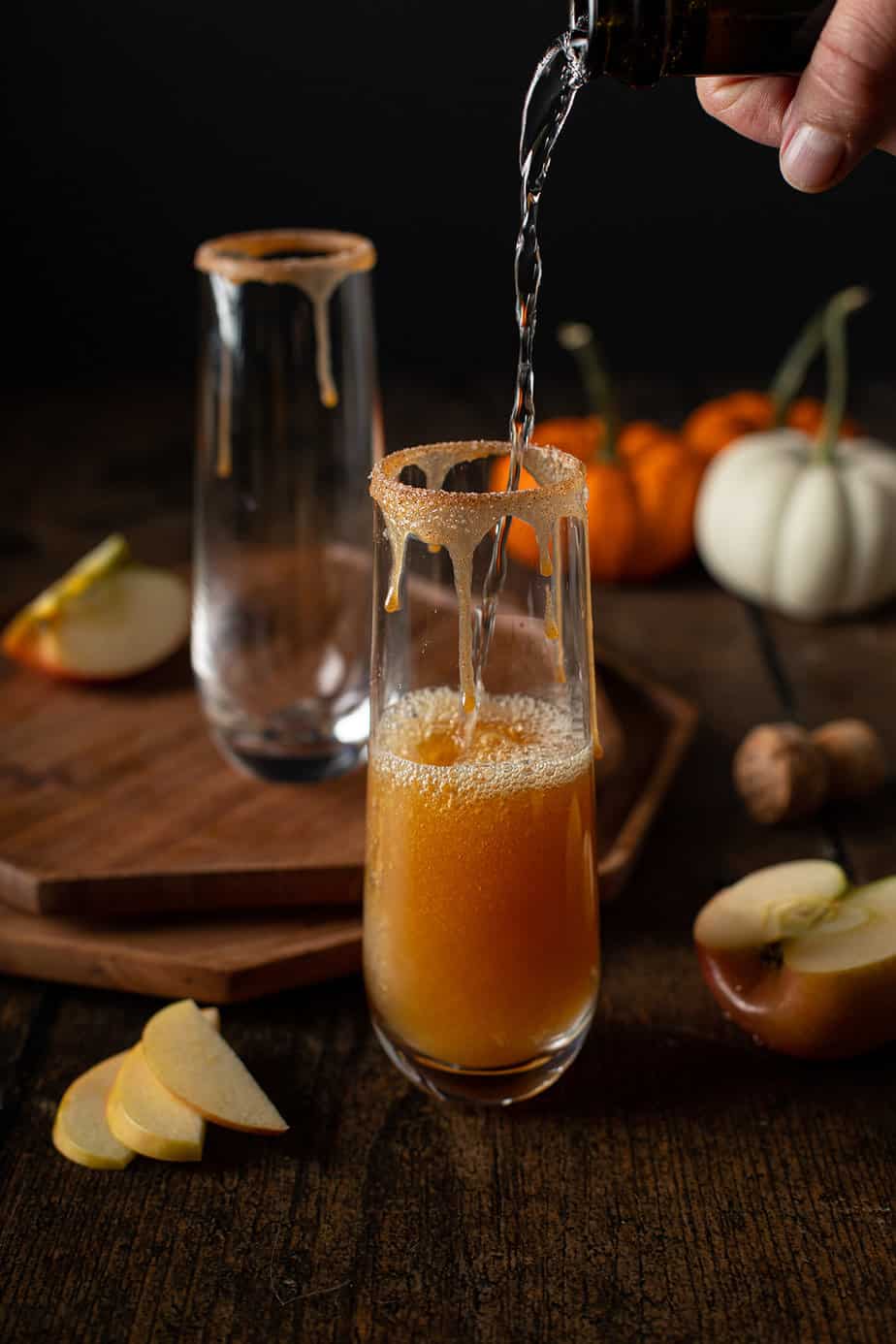 prosecco being poured into a stemless champagne flute over apple cider