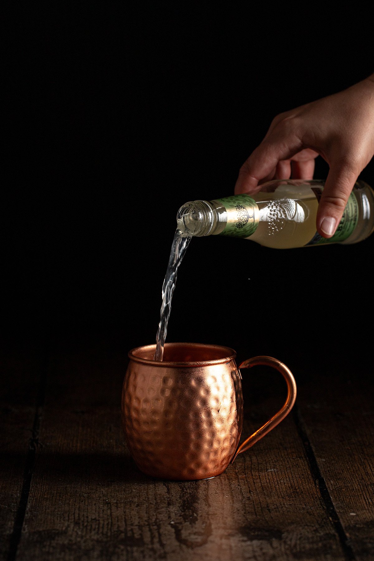 ginger beer being poured into a copper mug.