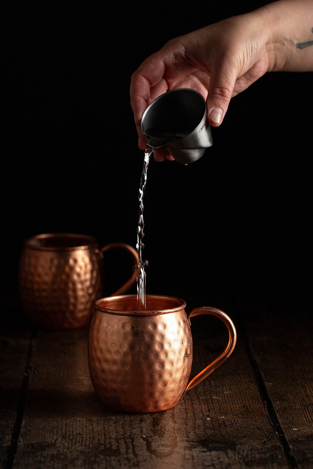 vodka being poured into a copper mug.