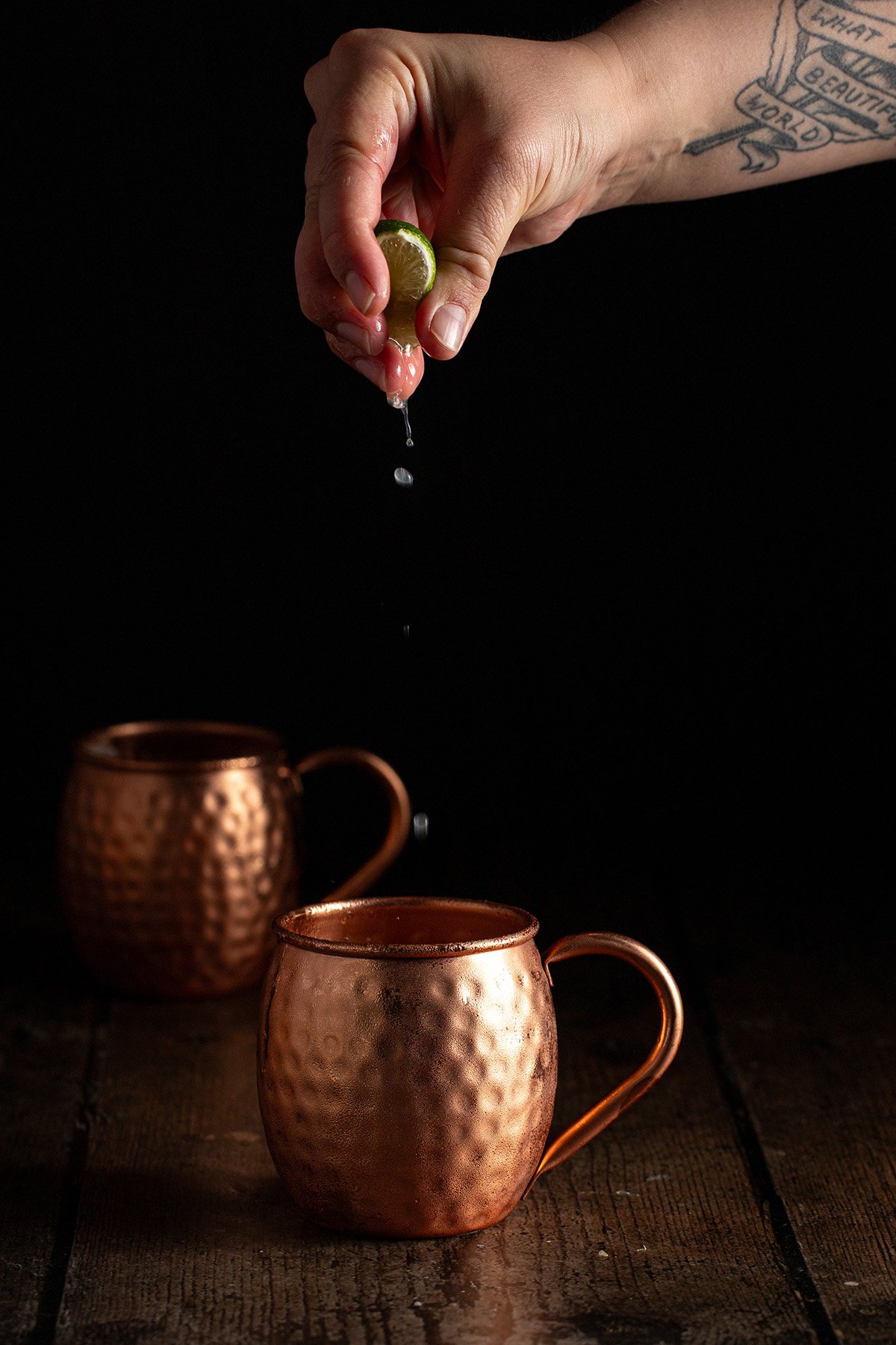 lime juice being squeezed into a copper mug.