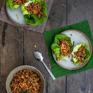 two plates with two pf changs chicken lettuce wraps each, a bowl with lettuce wrap filling