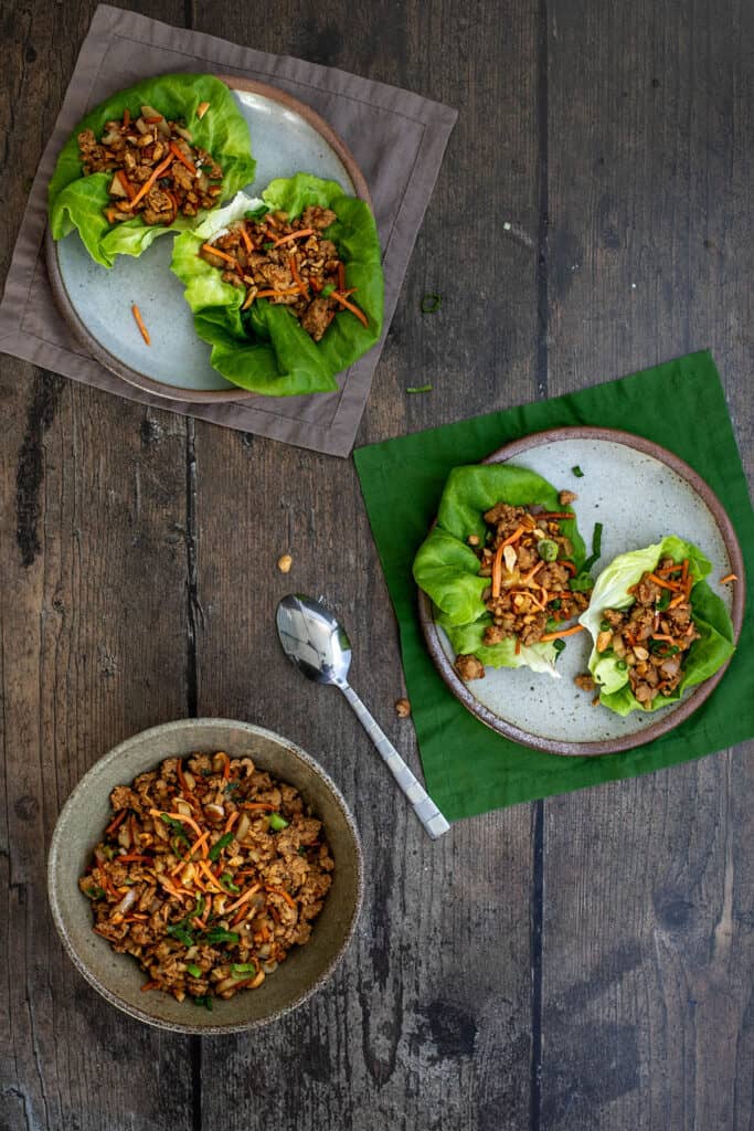 two plates with two pf changs chicken lettuce wraps each, a bowl with lettuce wrap filling