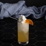 an orange creamsicle crush garnished with whipped cream and an orange wedge, plus a metal straw