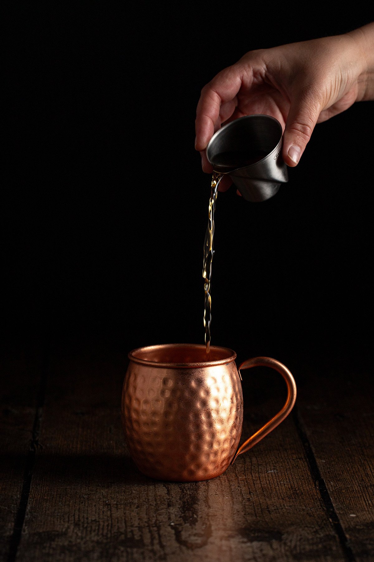 bourbon being poured into a copper mug.