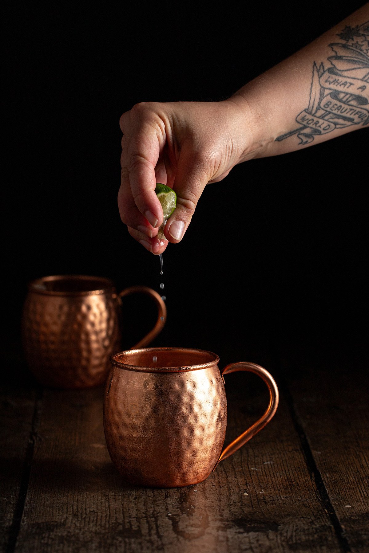 lime juice being squeezed into a copper mug.
