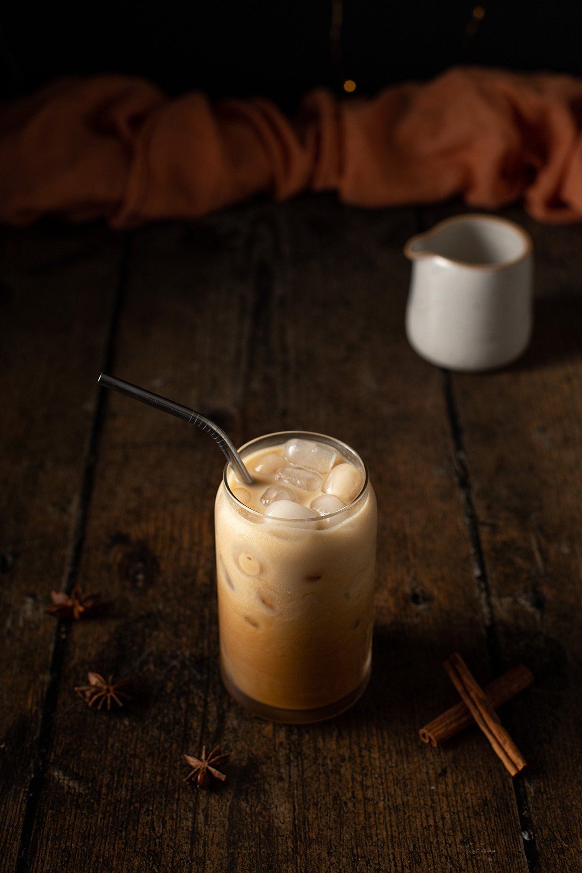 a 45 degree angle view of an iced chai latte with a metal straw