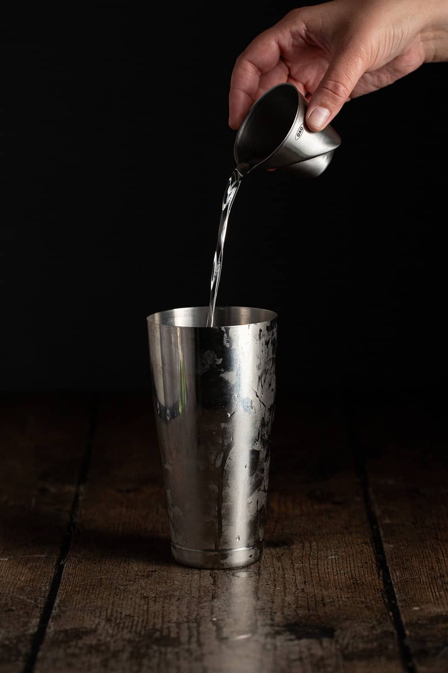 simple syrup being poured into a cocktail shaker