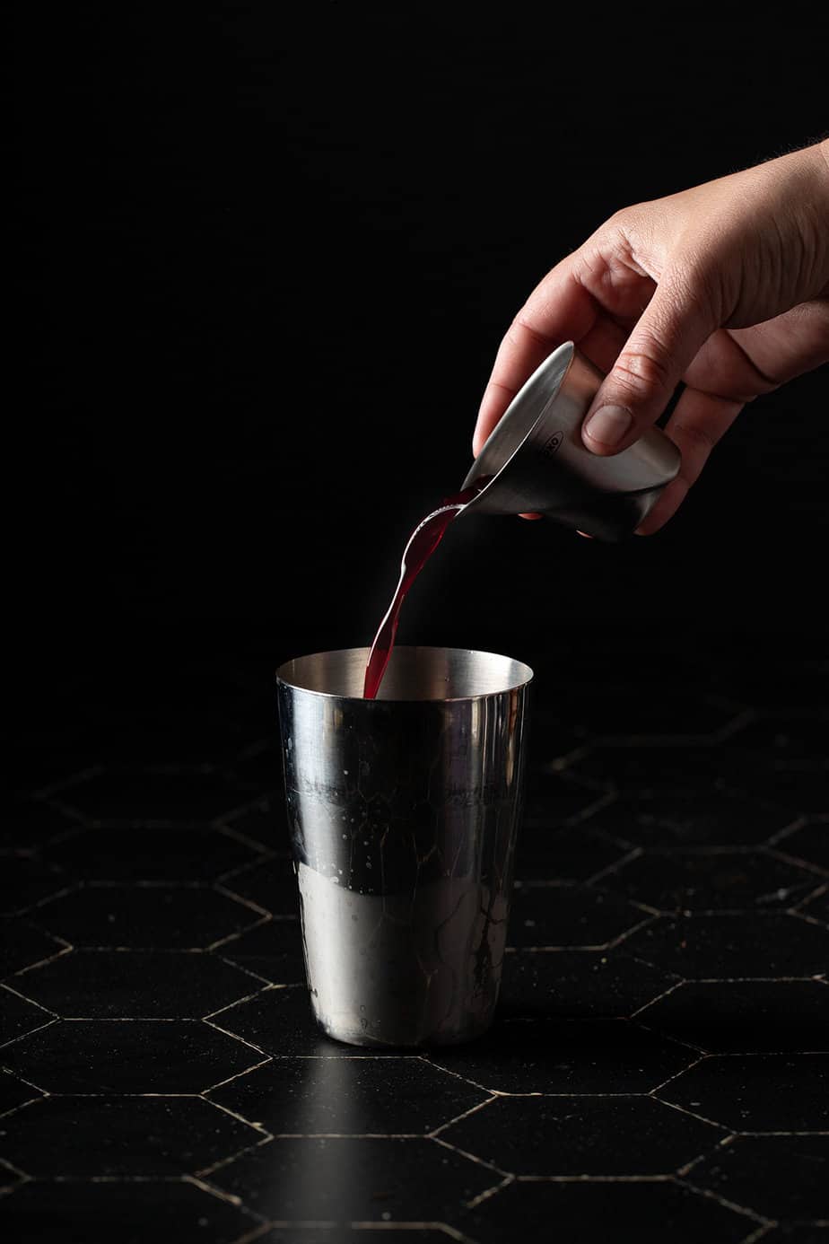 pomegranate juice being poured into a cocktail shaker