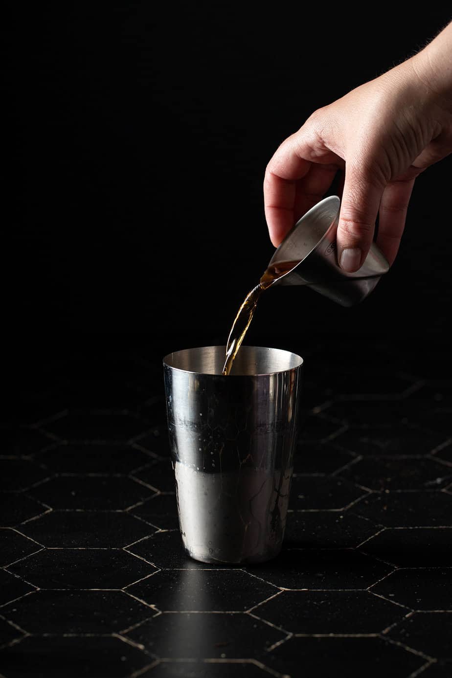 bourbon being poured into a cocktail shaker