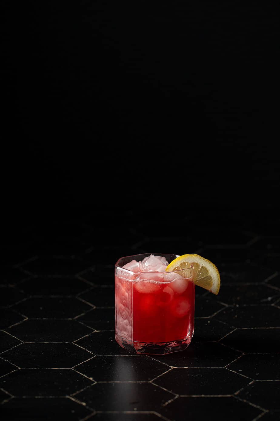 one rocks glass full of belmont jewel cocktail on a black background