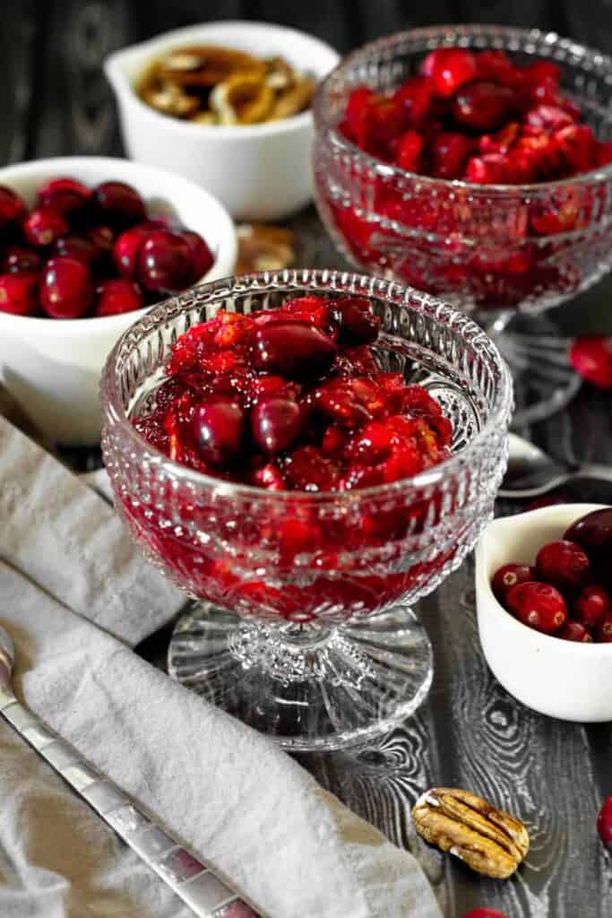 cranberry jello salad in a clear glass cup on a dark wood backdrop