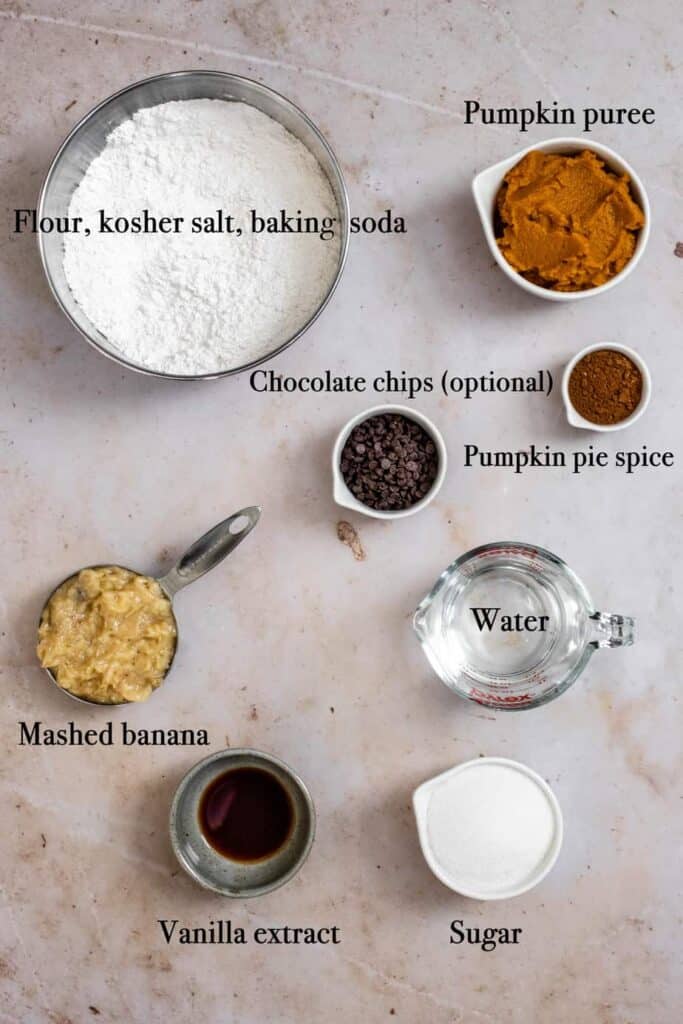 ingredients used to make pumpkin banana bread, photographed from above, labeled with black text, and set on a warm-colored background