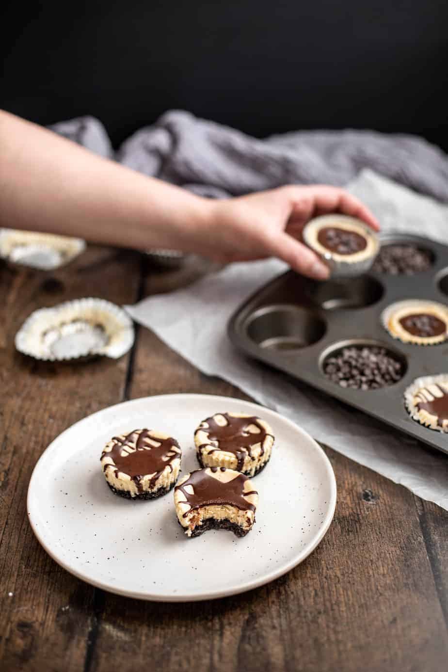 three mini cheesecakes on a plate, one with a bite taken out of it