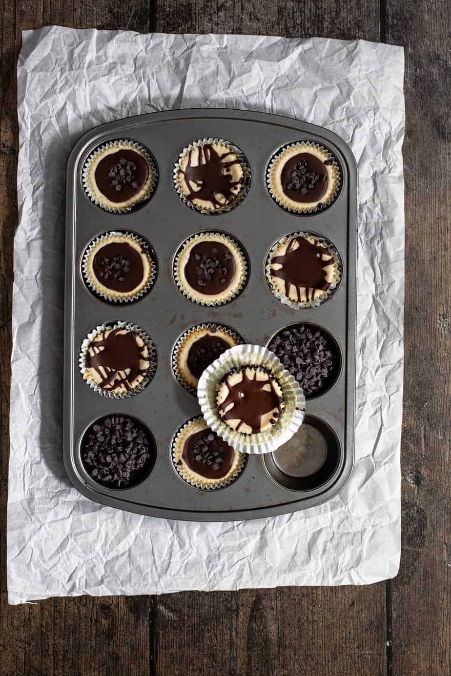 an overhead shot of a muffin tin that's full of mini cheesecakes