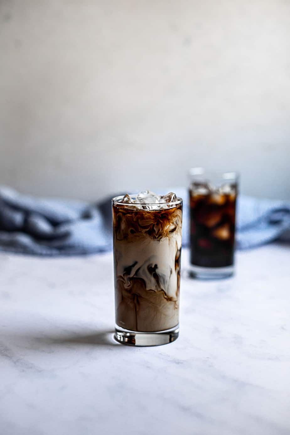 two glasses of iced coffee, one with cream