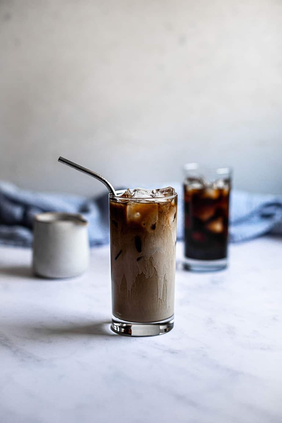 two glasses of iced coffee, one with cream and a straw