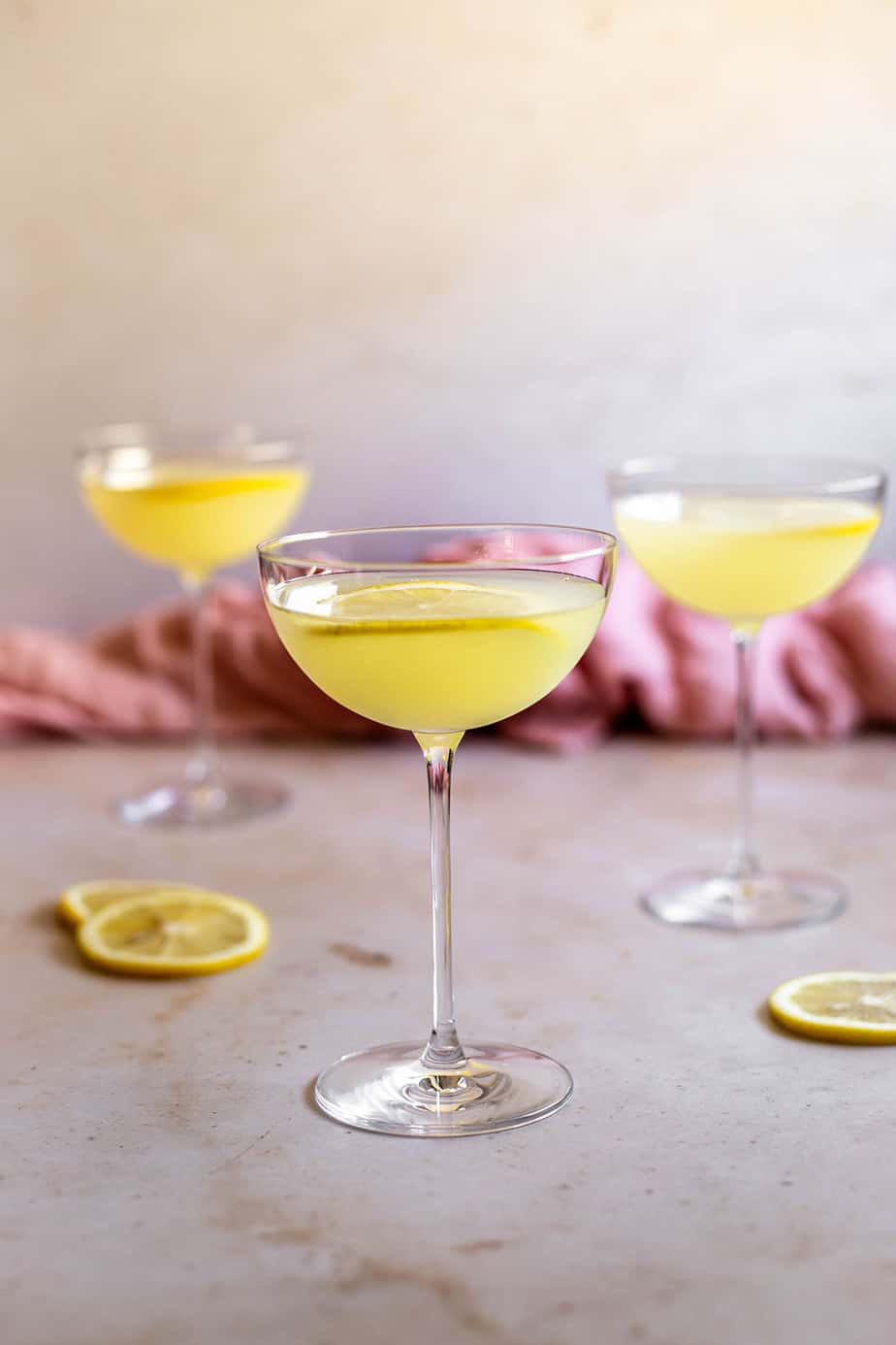 a straight on view of three coupe glasses filled with limoncello martinis and garnished with lemon slices