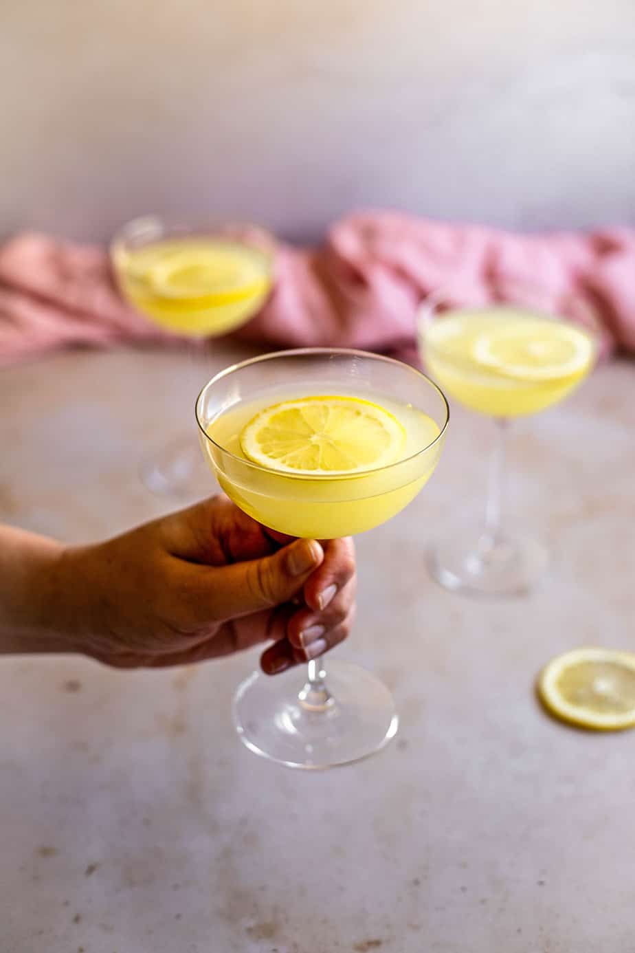 a hand holding a coupe glass with a limoncello martini in it