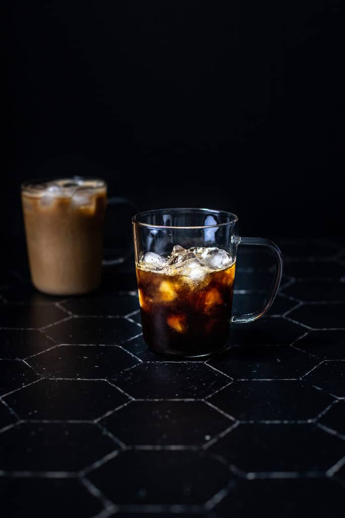 a clear glass mug filled with ice, espresso, and caramel syrup