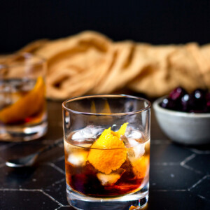 a maple old fashioned on a black tile background