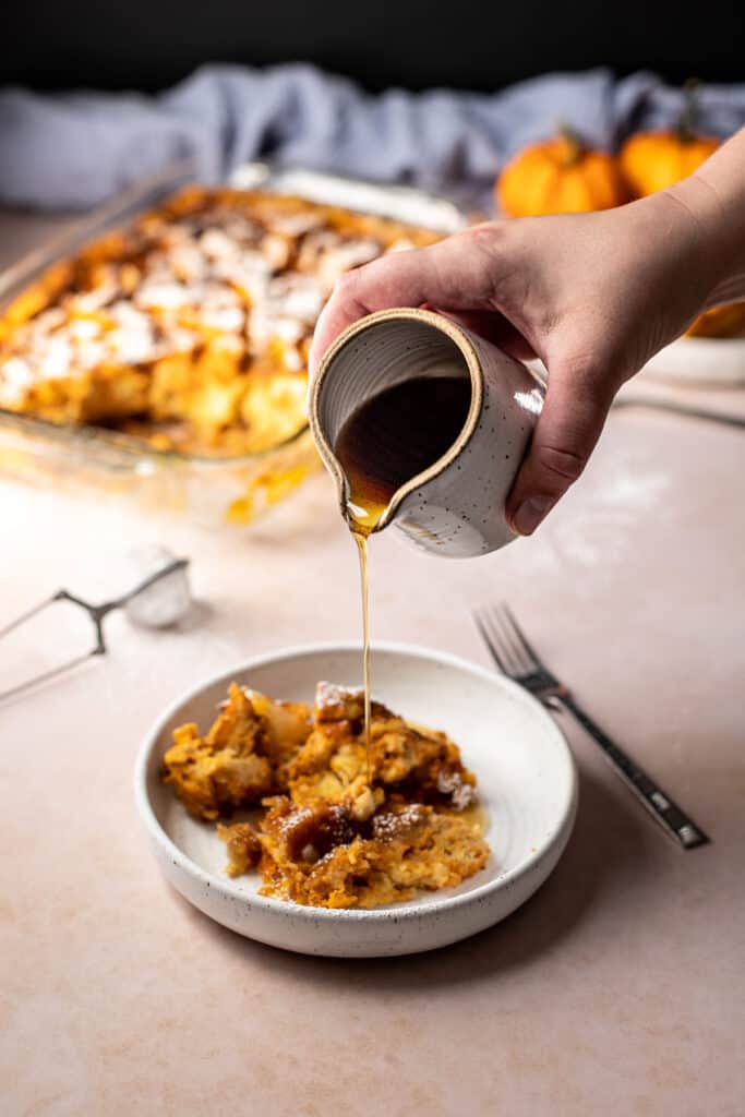 maple syrup being poured onto a portion of pumpkin french toast casserole