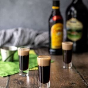 three baby guinness shots, with liqueur bottles in background.