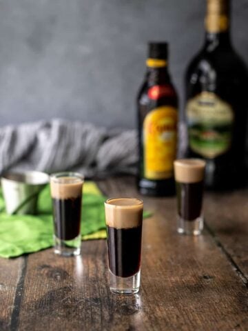three baby guinness shots, with liqueur bottles in background.