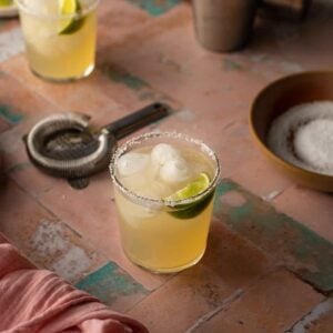 2 golden margaritas on a pink and green tile background