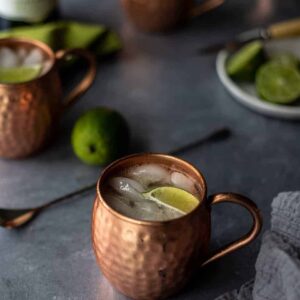 two Irish Mule cocktails in copper mugs on a gray background