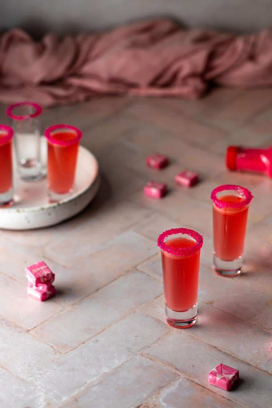 5 shot glasses, 4 filled with pink starburst shots