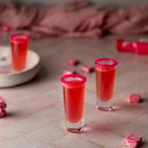 4 shot glasses, 3 filled with pink starburst shots