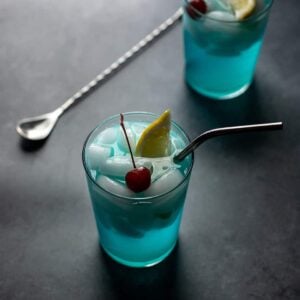 backlit photo of two glasses filled with a light blue liquid and ice