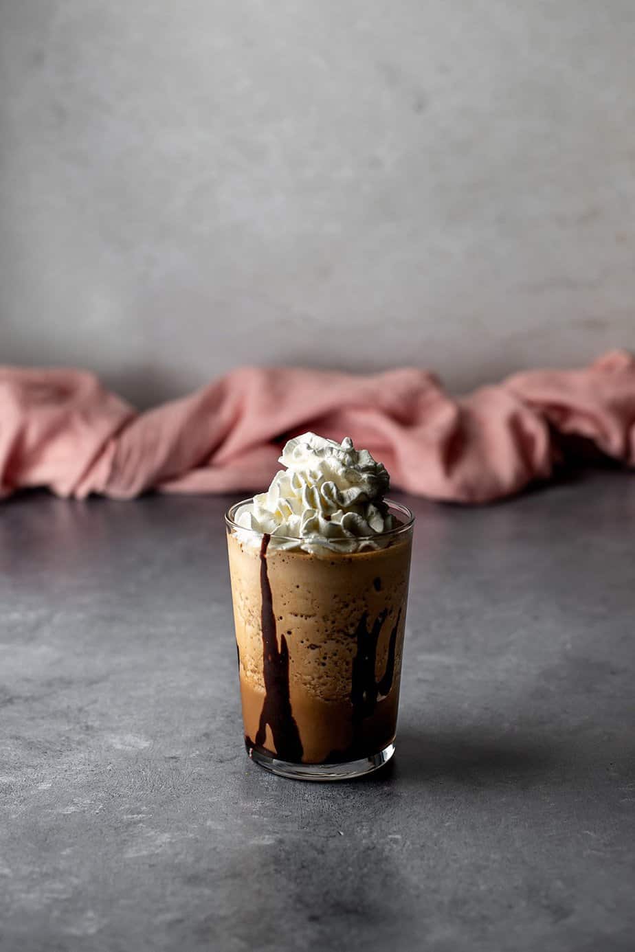 a java chip frappuccino in a glass, topped with whipped cream