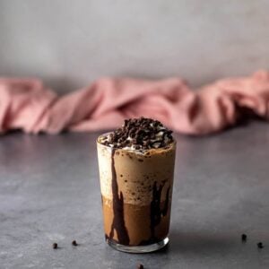 a java chip frappuccino in a glass, topped with whipped cream, chocolate sauce, and probably too many mini chocolate chips