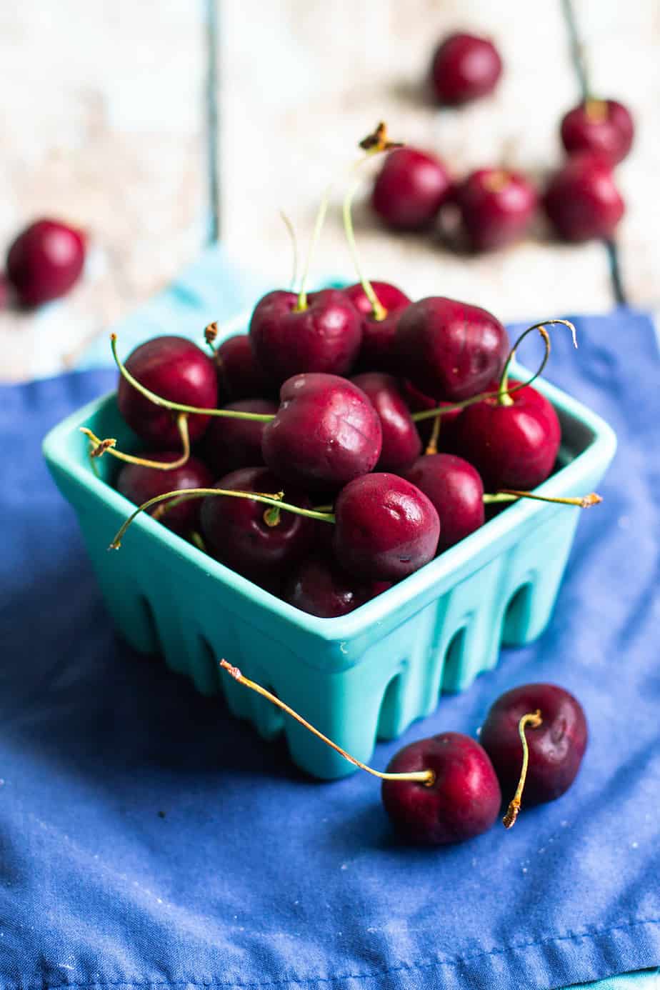 little blue basket full of red cherries