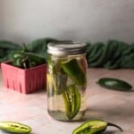 a mason jar filled with silver tequila and sliced jalapeños