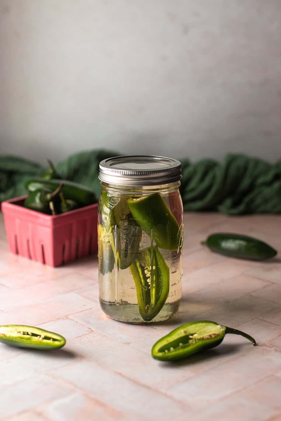 a mason jar filled with silver tequila and sliced jalapeños