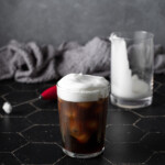 a glass of cold brew coffee topped with cold foam.