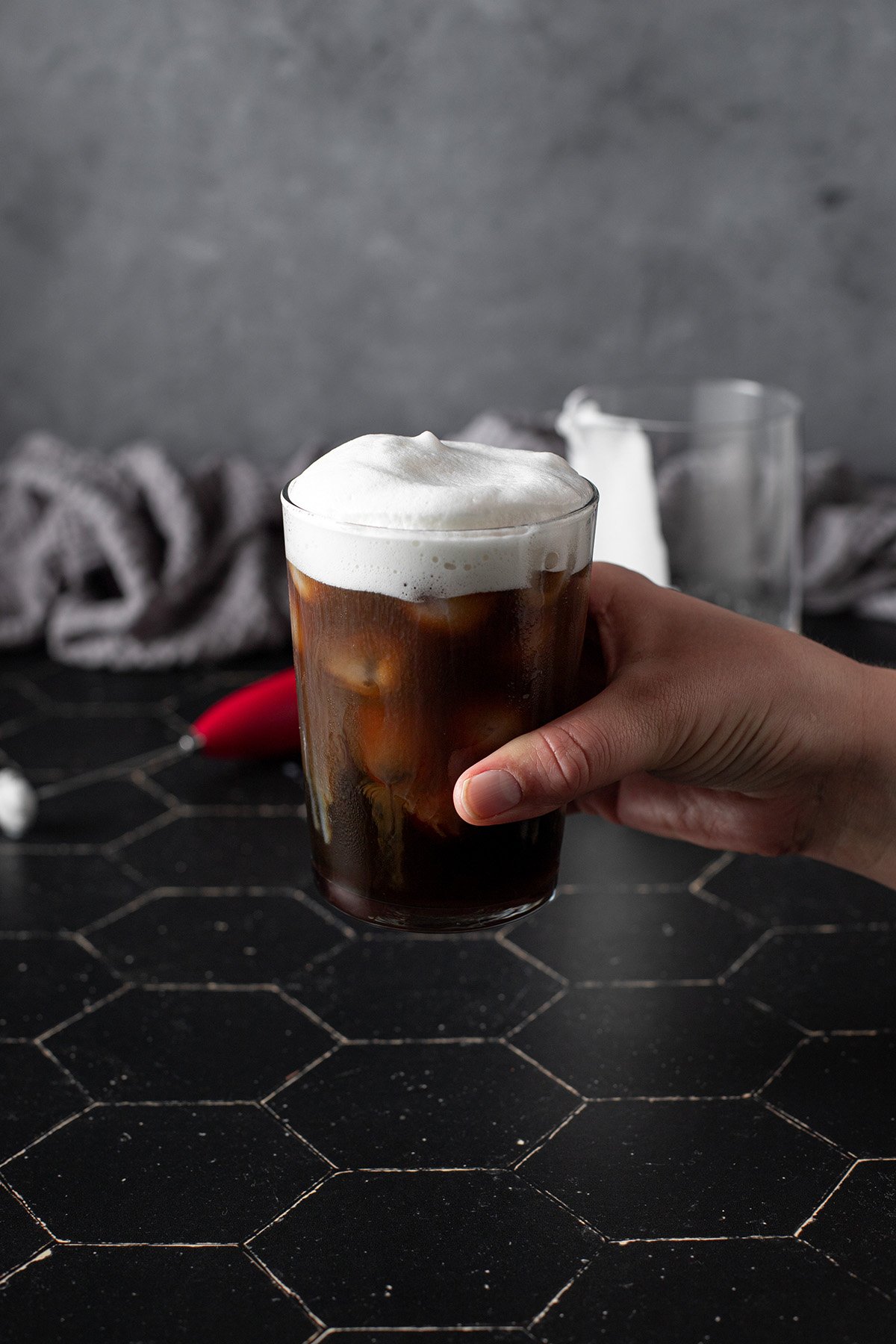 hand holding a glass of cold brew with cold foam