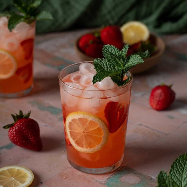 a glass of strawberry lemonade vodka cocktail garnished with mint