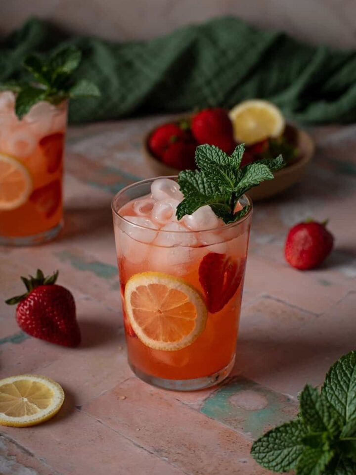 a glass of strawberry lemonade vodka cocktail garnished with mint