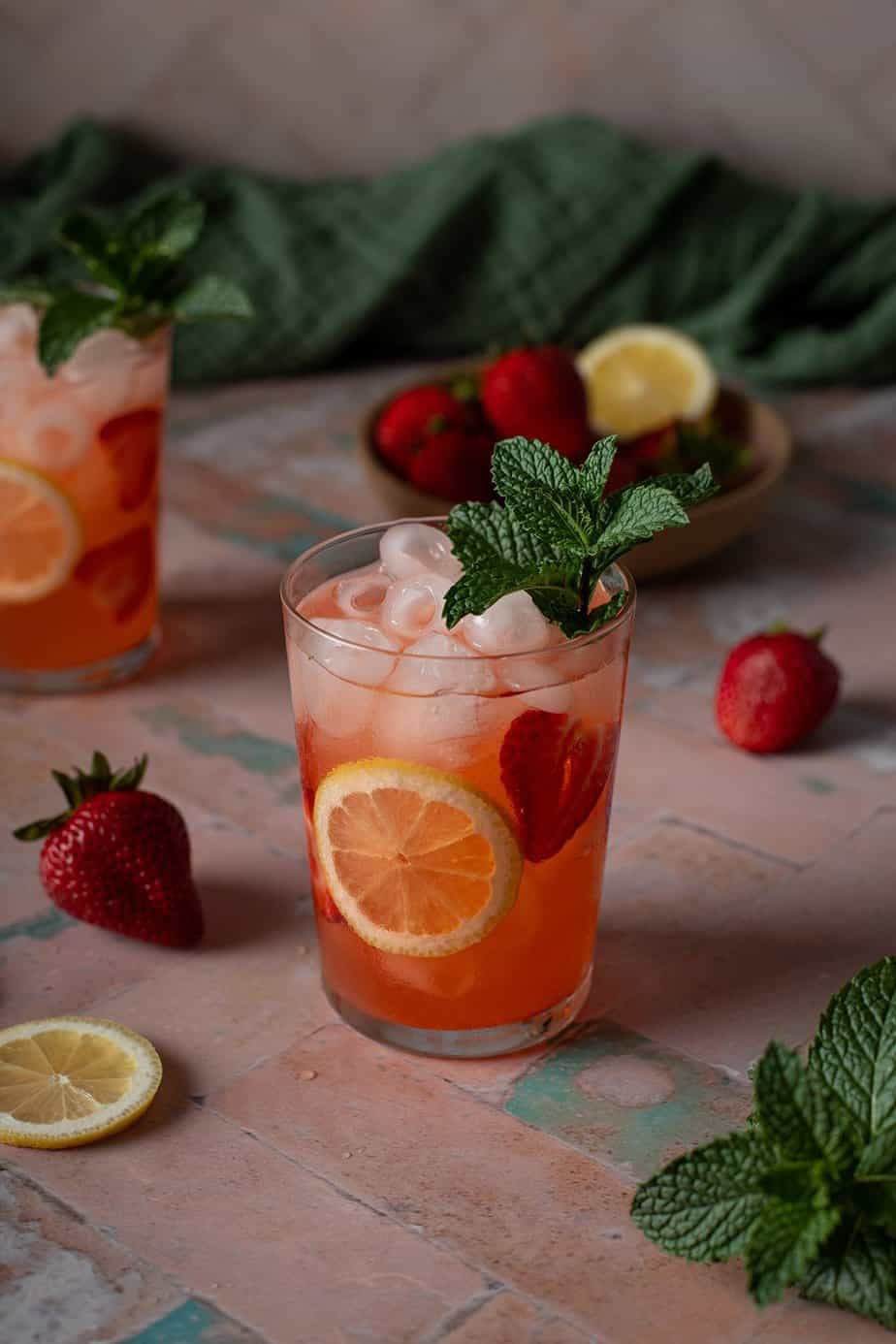 a glass of strawberry lemonade vodka cocktail garnished with mint