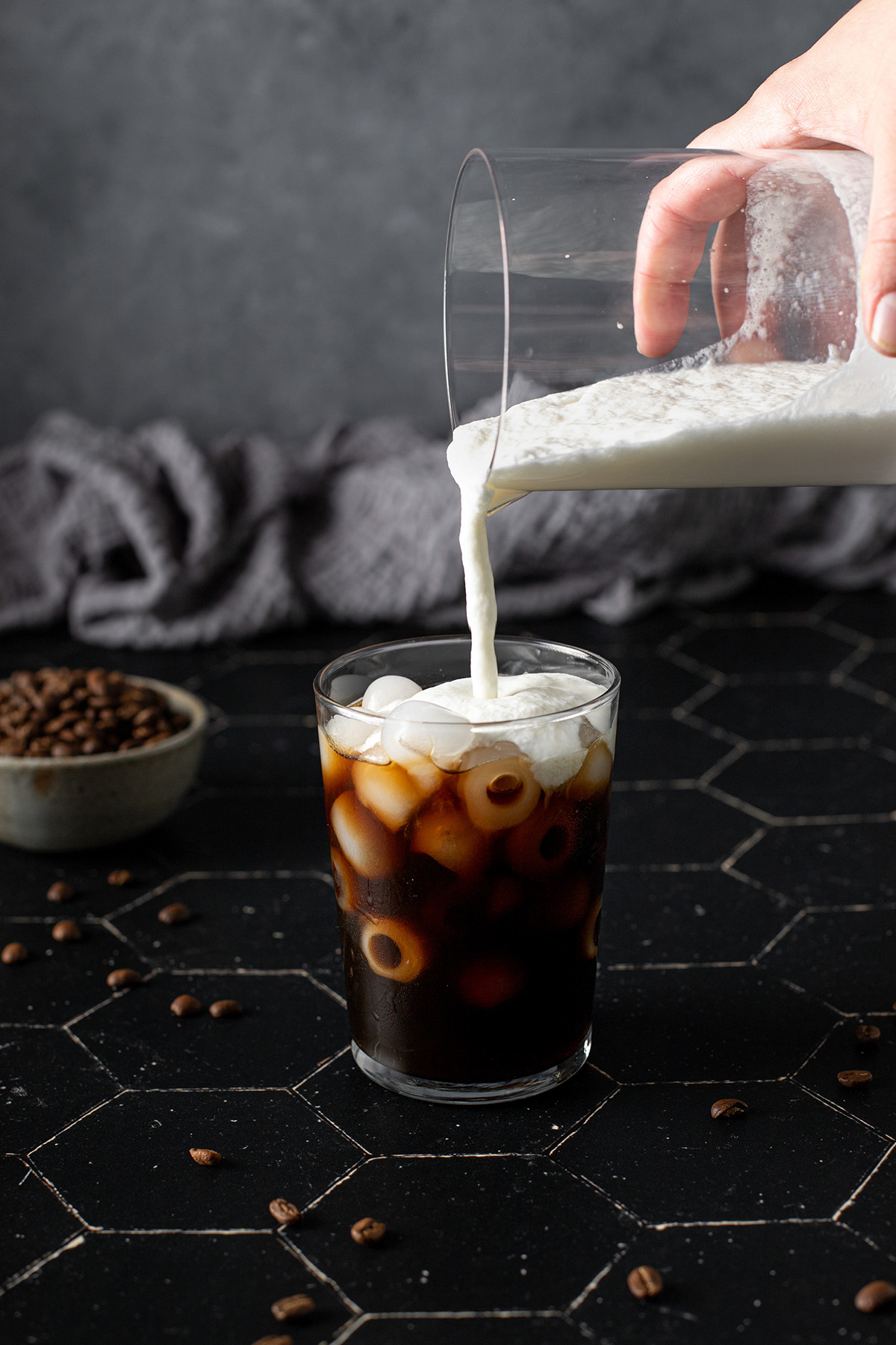 vanilla sweet cream cold foam being poured onto a glass of ice and cold brew coffee