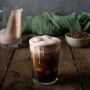 a glass of cold brew coffee topped with chocolate cream cold foam