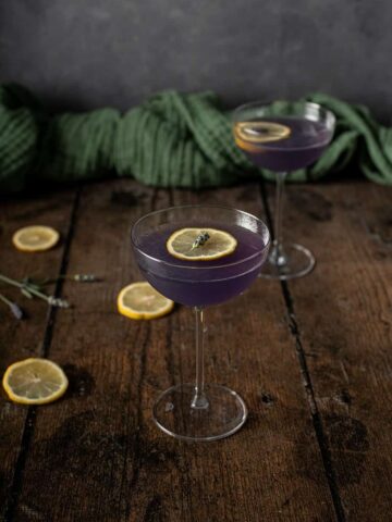 a nearly head on view of 2 coupe glasses full of lavender martinis