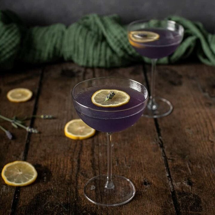 a nearly head on view of 2 coupe glasses full of lavender martinis