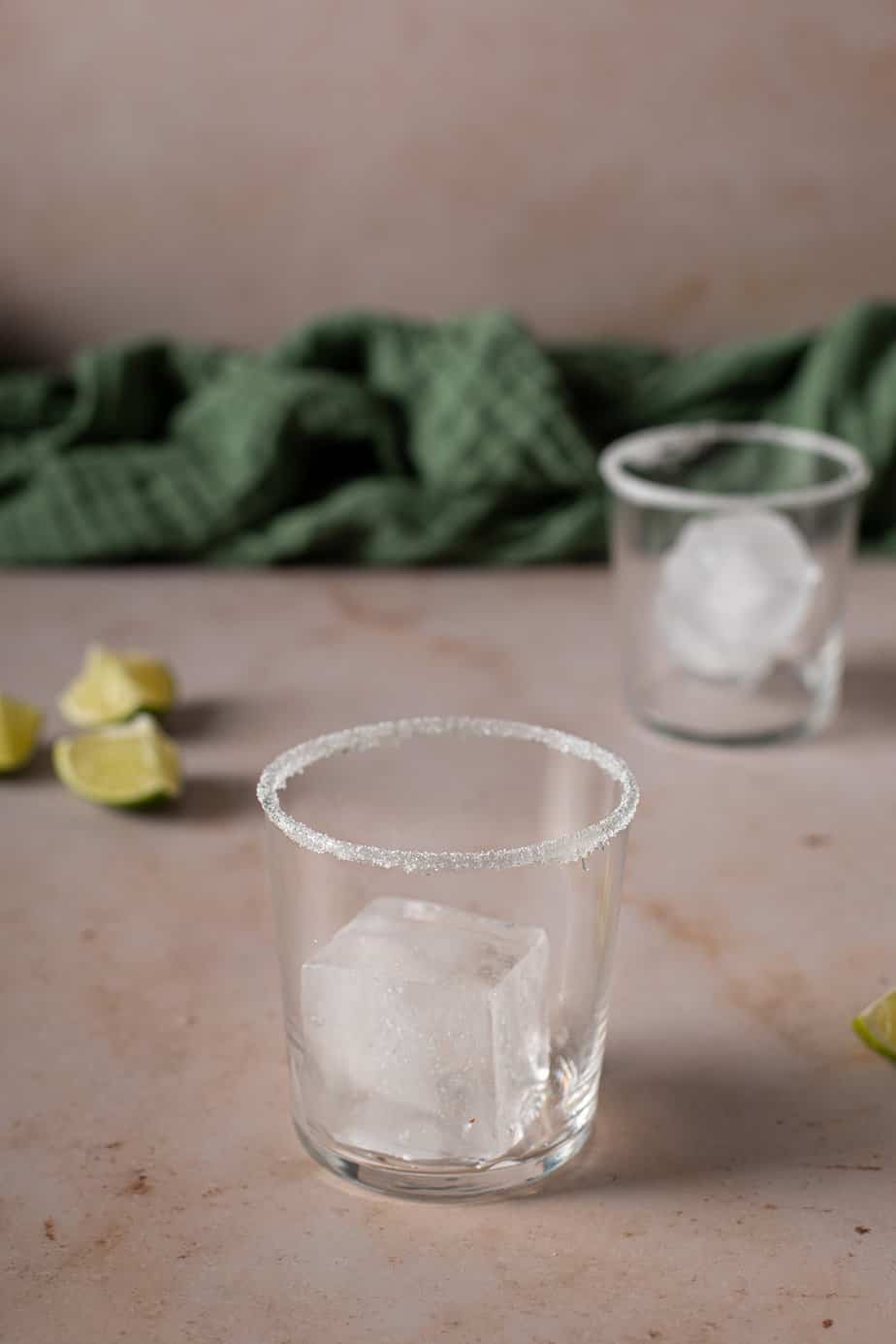 two empty glasses, with large ice cubes, rimmed with salt
