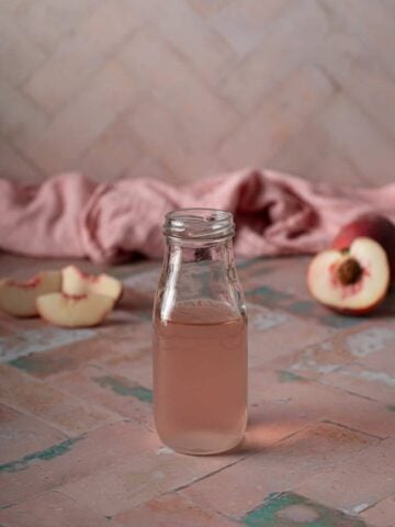 a small glass jar filled with peach simple syrup