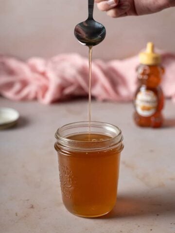 jar full of honey syrup, a spoon is drizzling more syrup into the jar