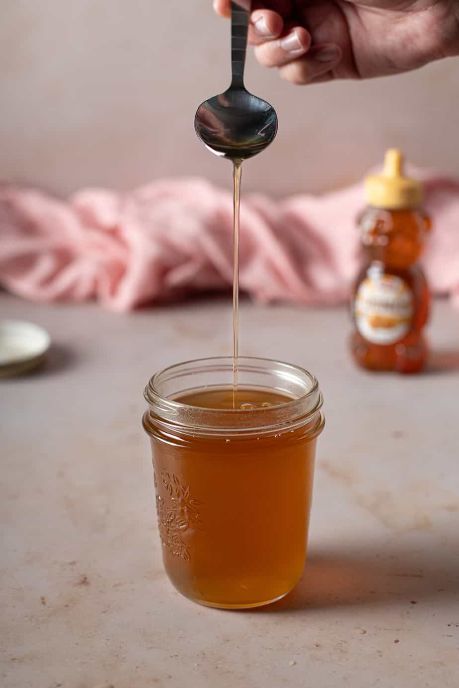 jar full of honey syrup, a spoon is drizzling more syrup into the jar